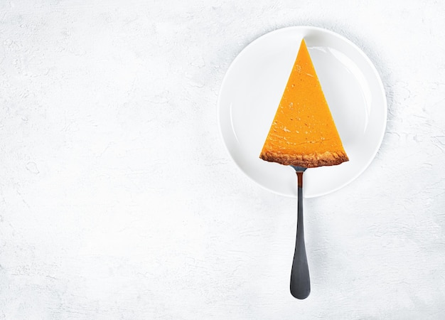 Cut slice of pumpkin pie on plates on a light background