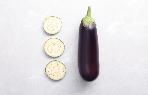 Photo cut and whole raw ripe eggplants on light table flat lay