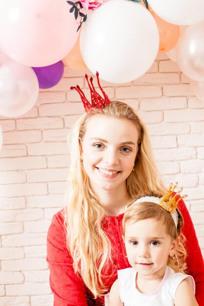 Cuta moeder met haar dochter die verjaardag viert met kronen op de hoofden