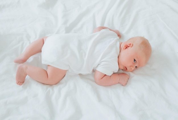 Cute 2monthold baby lying on the bed natural bed linen delicate baby skin