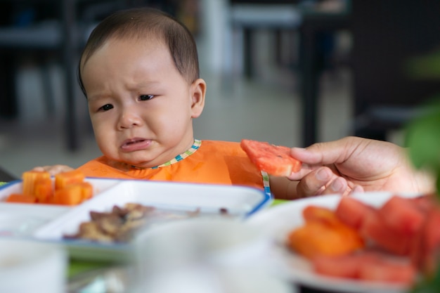 Photo cute 5-6 month asian baby girl doesn't want to eat watermelon