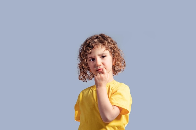 Cute 5 year kid in yellow tshirt turning her head on gray