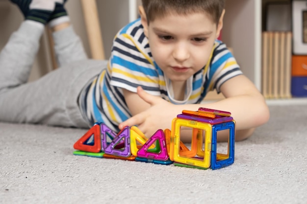 A cute 5 year old boy creates figures with a magnetic construction kit