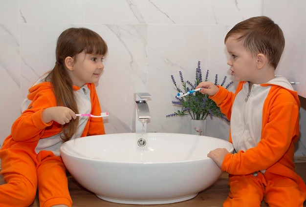 Neonata adorabile sveglia che tiene uno spazzolino da denti e si lava i denti in bagno. il bambino impara a rimanere in buona salute. sana igiene mattutina per i bambini.