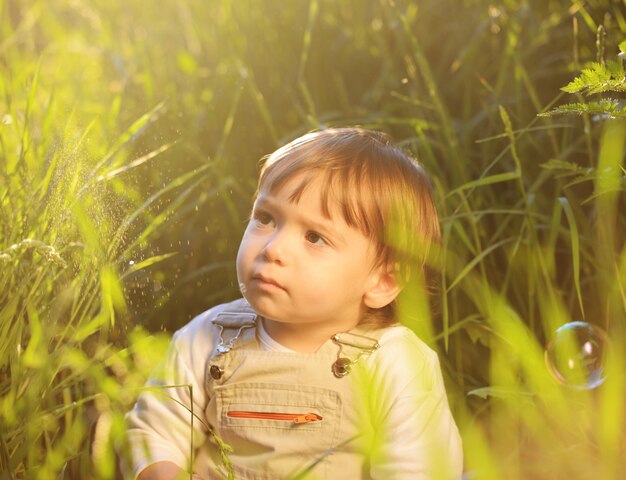 美しい緑の草に座っているかわいい愛らしい赤ちゃんの子供