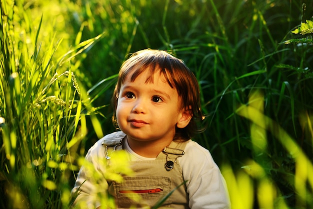 Cute adorable baby kid sitting in beautiful green grass