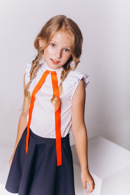 Cute adorable caucasian blondie girl in school uniform on white background