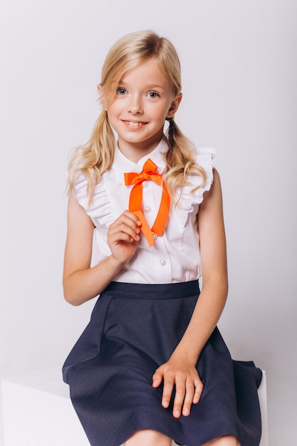 Cute adorable caucasian blondie girl in school uniform on white background