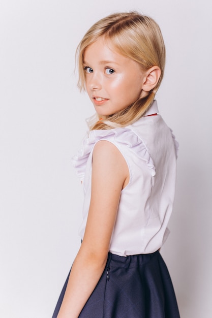 Cute adorable caucasian blondie girl in school uniform on white background