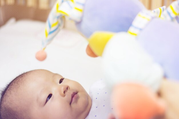 Cute adorable newborn baby playing on colorful toy gym 