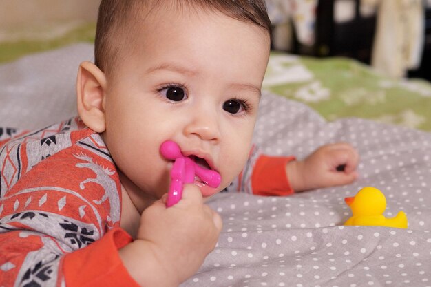 Cute adorable newborn baby playing with colorful rattle toy baby with teether six months old lovely baby portrait on white with teether toy