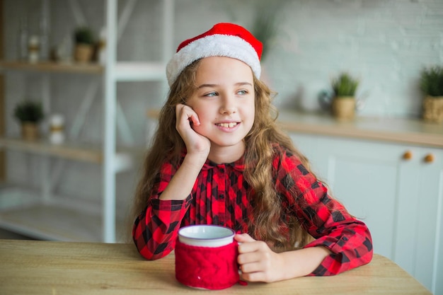 Foto carina adorabile ragazza sorridente con il cappello di babbo natale a casa