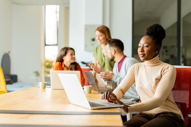 Cute Africam American woman with her young multiethnic startup team working at the modern office