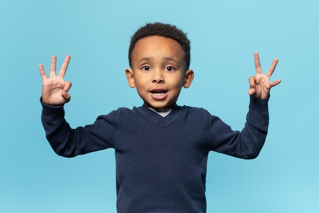 Cute african american boy showing ok gesture with both hands posing isolated on blue background studio shot