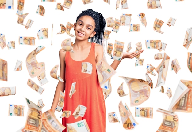 Cute african american girl wearing casual clothes smiling cheerful presenting and pointing with palm of hand looking at the camera.