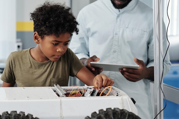 おもちゃのロボットのケーブルを接続するかわいいアフリカ系アメリカ人の少年