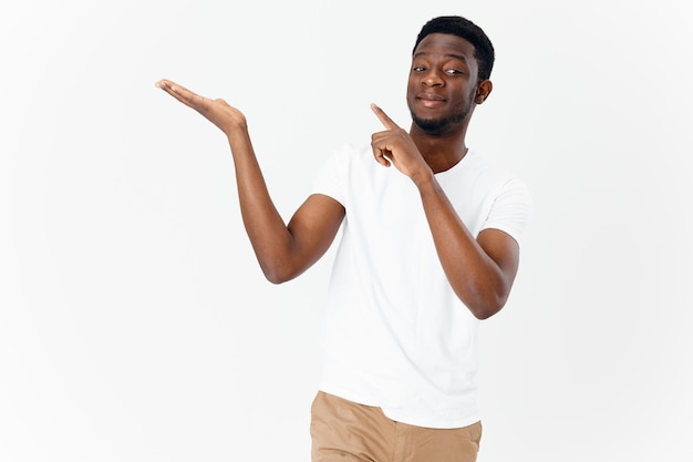 Cute african man in white tshirt gesturing with hands on light background cropped view