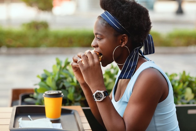 街のカフェで外で昼食をとっている可愛いアフリカ人女性