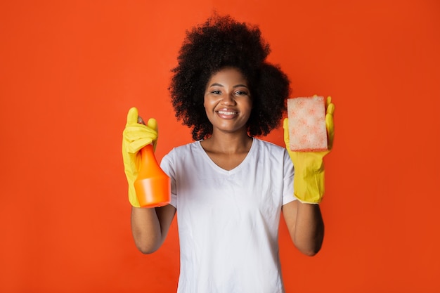 Cute african woman with afro hairstyle with spray and sponge in her hands