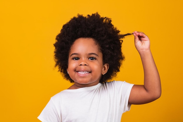 カメラに微笑んでいる黒い力の髪を持つかわいいアフロの女の子。ブラックデー。こどもの日