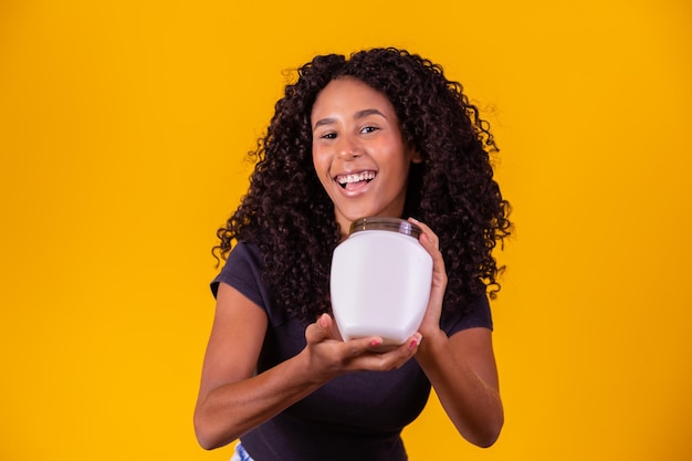 Cute afro girl with curly hair with a bottle of moisturizing\
cream afro woman with a moisturizing mask for afro hair