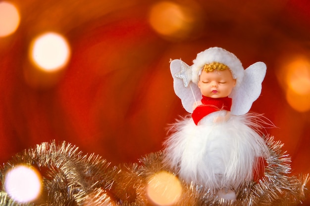 Фото Симпатичные рождественские украшения ангела на красном фоне. скопируйте пространство. открытка. новый год и счастливого рождества
