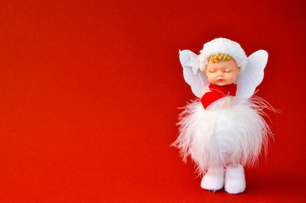 赤い背景のかわいい天使のクリスマスの装飾。スペースをコピーします。グリーティングカード。新年とメリークリスマス