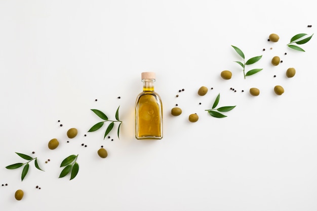 Cute arrangement of leaves and olive oil on white background