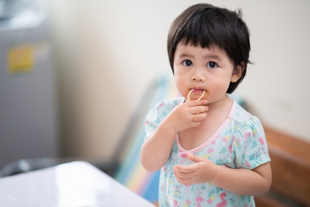 Cute asian baby eating spaghetti in the dinning room