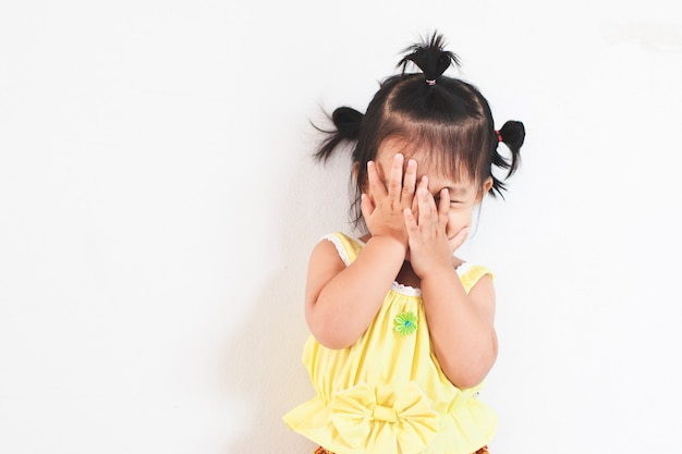 Cute asian baby girl closing her face and playing peekaboo or hide and seek with fun