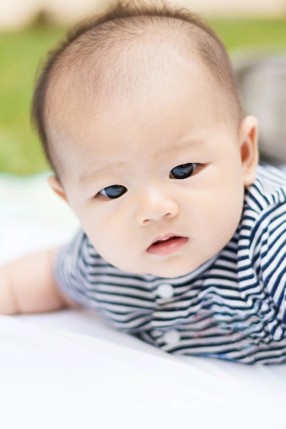 cute Asian baby lie prone on ground at park