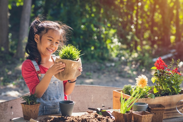 かわいいアジアの子供の女の子は植物の世話をします。家でガーデニングをしている娘。春の日の人々の自然の概念で幸せな休日の家族。