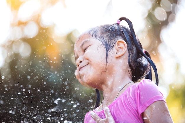 Cute asian child girl having fun to bath and playing water splash in outside