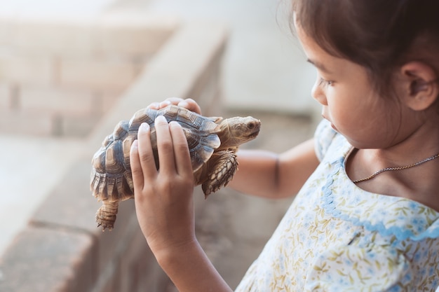 Фото Симпатичные азии девочка держит и играет с черепахой