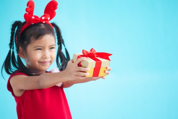 かわいいアジアの子供の女の子がクリスマスのお祝いの上に手に美しいギフトを持って