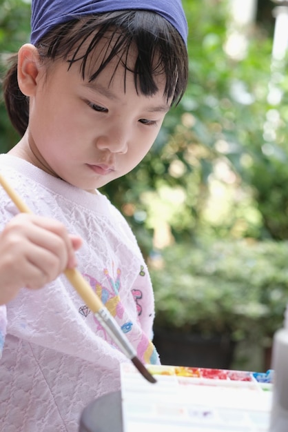 写真 可愛いアジアの子供の女の子がペイントブレスを持って紙に絵を描いています 選択的な焦点