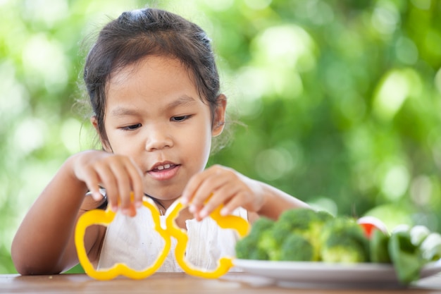 Cute asian child girl learning about vegetables with happiness