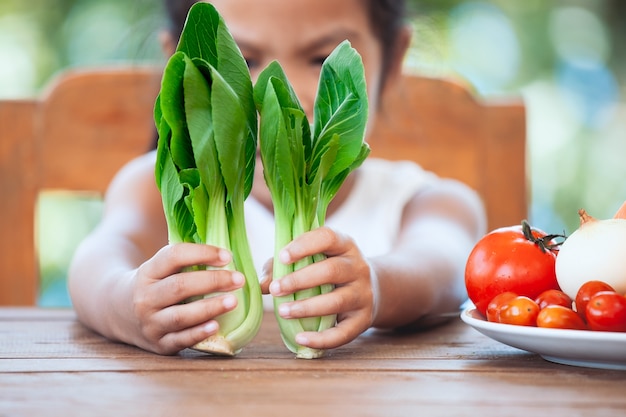Cute asian child girl learning about vegetables with happiness