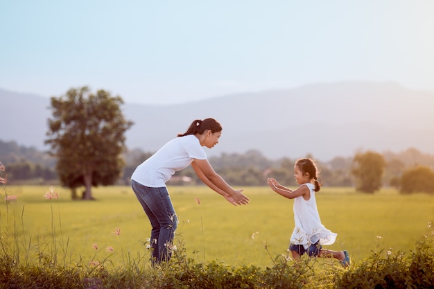 Cute asian child girl running to her mother to give a hug in the field in vintage color tone