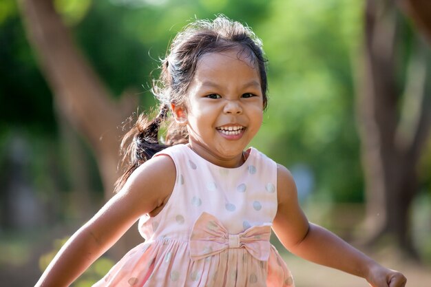 かわいいアジアの子供の女の子が公園で走っている