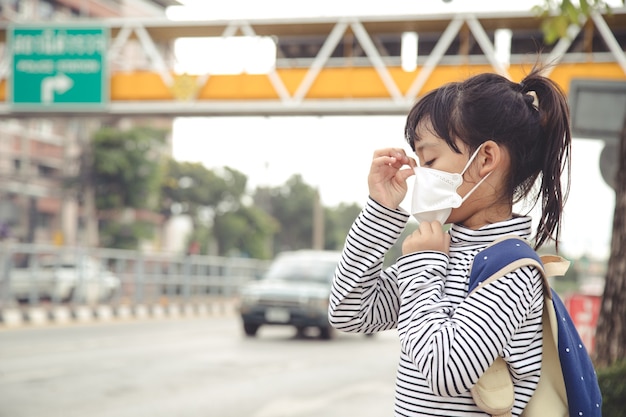 사진 도시에서 pm 2.5로 대기 스모그 오염을 방지하기 위해 보호 마스크를 쓴 귀여운 아시아 소녀