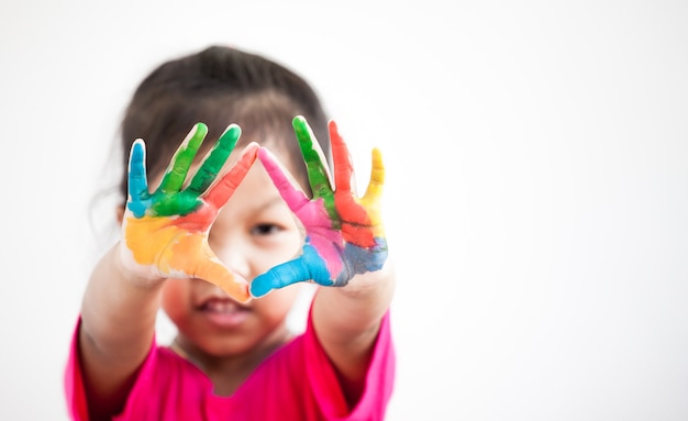 Cute asian child girl with hands painted in colorful paint on white background