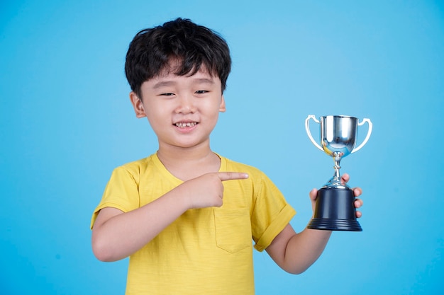 Cute Asian child holding up a trophy