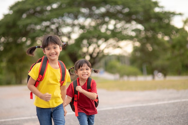 Cute Asian children holding hand together while going to the school