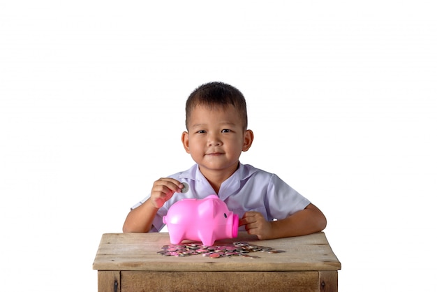 Cute asian country boy putting coins into piggy bank isolated on white background