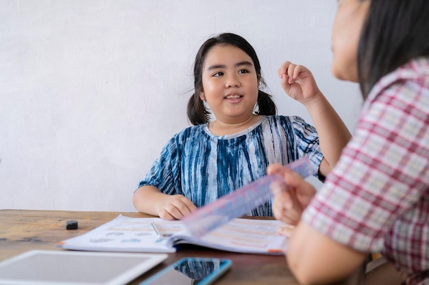 A cute Asian female student studying closely with her teacher She is telling the teacher a question