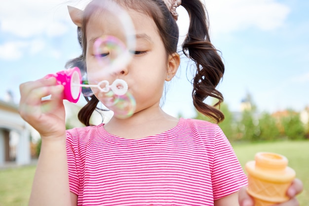 Cute Asian Girl Blowing Bubbles Outdoors