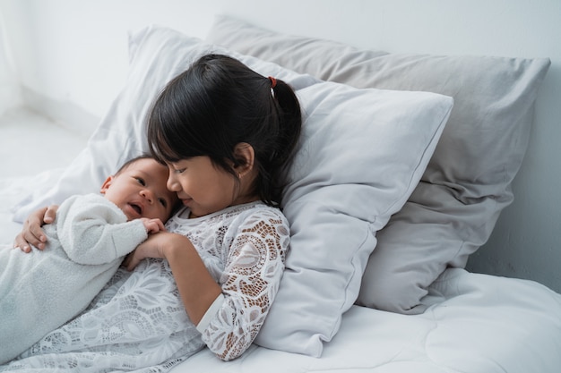 Cute Asian girl laying on the bed with his baby brother