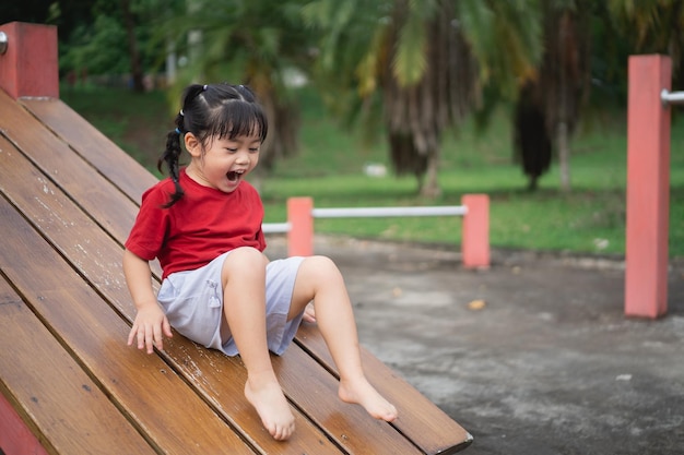 Cute asian girl play on school or kindergarten yard or playground Healthy summer activity for children Little asian girl climbing outdoors at playground Child playing on outdoor playground