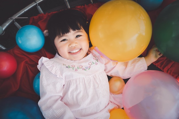 Cute asian girl play on school or kindergarten yard or\
playground. little asian girl playing colorful ball at playground.\
child playing on outdoor playground.